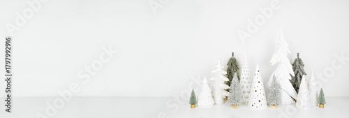 Green and white Christmas tree decor on a white shelf against a white wall banner background with copy space