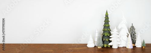 Green and white Christmas tree decor on a wood shelf against a white wall banner background with copy space