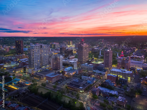 The dramatic twilight sky drapes the New Haven, Connecticut, skyline in deep blue and orange hues as city lights illuminate the scene.