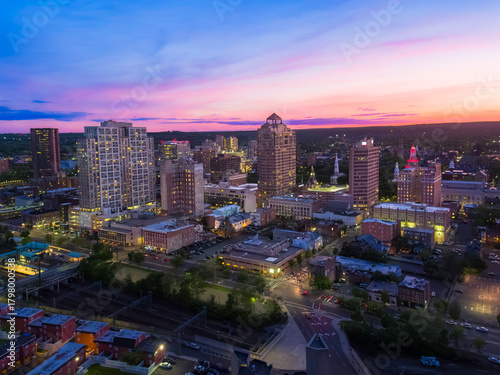 The dramatic blue hour sky drapes the New Haven, Connecticut, skyline in deep blue and orange hues as city lights illuminate the scene.