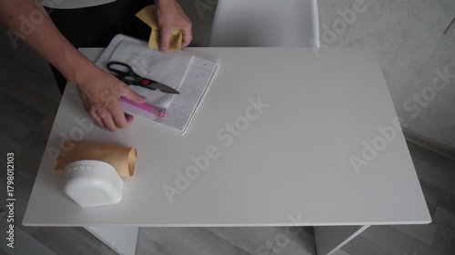 Unrecognizable man wipes a white table, a cleaner disinfects and wipes the table with a rag, top view