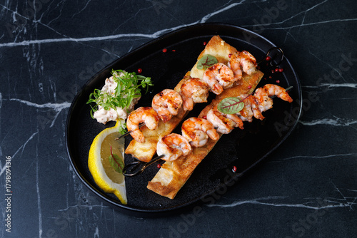 Gourmet Shrimp Skewers on Crispy Bread with Lemon Wedge and Fresh Green