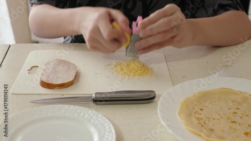 Unrecognizable person preparing cheese dish morning, hands are crafting breakfast with cheese, ham and pancake ingredients, cozy kitchen environment