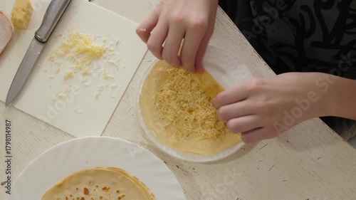 Cheese roll breakfast, rustic kitchen scene with crafting cheesefilled crepe, top view. Hands preparing cheese filled pancake, rustic kitchen with hands rolling cheesy crepe on wooden countertop