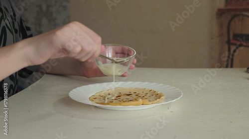 Cozy morning kitchen with pancake and condensed milk, close-up of filling being poured on pancake in warm environment, breakfast scene showing adding delicate tasty filling