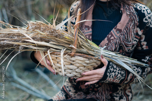 una donna tiene in braccio un cesto con canne in autunno