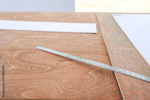 Ruler is on a wooden table next to a piece of paper