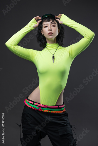 Cyberpunk model in bright green bodysuit and athletic pants on neutral background