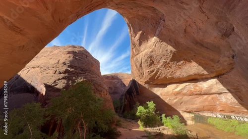 Sunlight pouring through Jacob Hamblin Arch with blue sky and streaked clouds