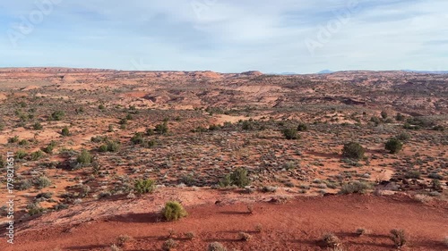 Wide desert vista with red rock mesas and sparse vegetation