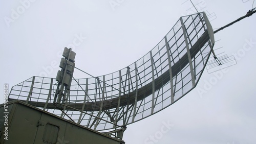 industrial radar system scanning sky above, large antenna on platform monitors drones and airplanes