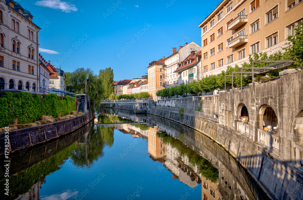 Fototapeta premium Ljubljana, Slovenia – July 14, 2025: A scenic view of the Ljubljanica River as it winds through the historic center of Ljubljana.
