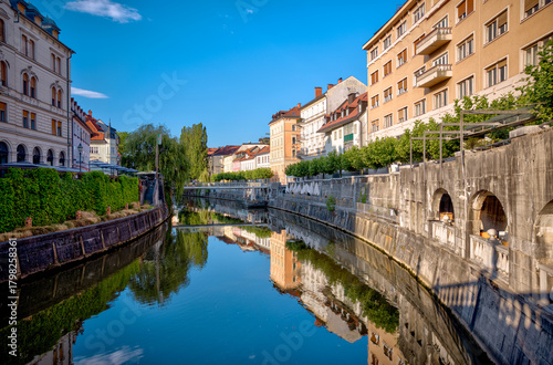 Fototapeta Naklejka Na Ścianę i Meble -  Ljubljana, Slovenia – July 14, 2025: A scenic view of the Ljubljanica River as it winds through the historic center of Ljubljana.