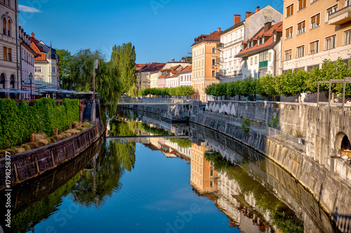 Fototapeta Naklejka Na Ścianę i Meble -  Ljubljana, Slovenia – July 14, 2025: A scenic view of the Ljubljanica River as it winds through the historic center of Ljubljana.