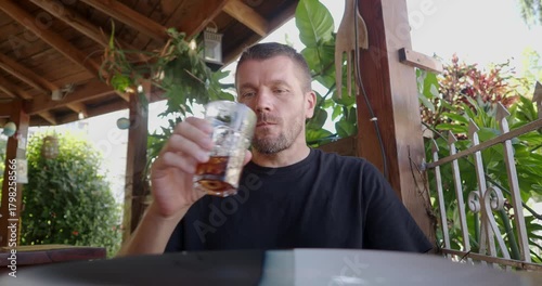 Man enjoying a cold drink in a cozy outdoor cafe while waiting order.