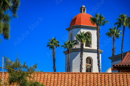 Mission San Juan Capistrano orange dome rises above tile roofs and palm trees