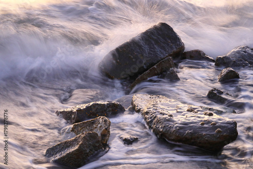 Fototapeta Naklejka Na Ścianę i Meble -  Small rocks in the sea among the waves. The sea has a veil effect with the long exposure technique.