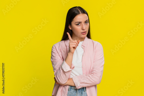 Young woman angrily waving finger and shaking head with disapproving expression clearly showing dissatisfaction and strong rejection. Girl on yellow background demonstrates emotional frustration anger