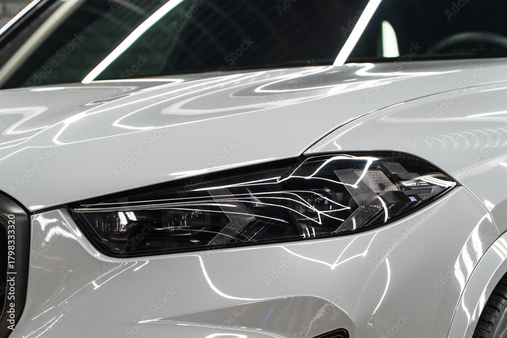 Fototapeta premium Close up detail on one of the LED Laser headlights modern white car. Exterior close up detail. Headlights of car. BI-LED Laser headlights of a modern white car. Front BI-LED headlight on sport car.