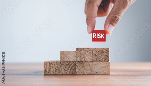 Wallpaper Mural Hand placing a red RISK block on a wooden stair-step structure, symbolizing business risk management and strategic decision-making. Torontodigital.ca