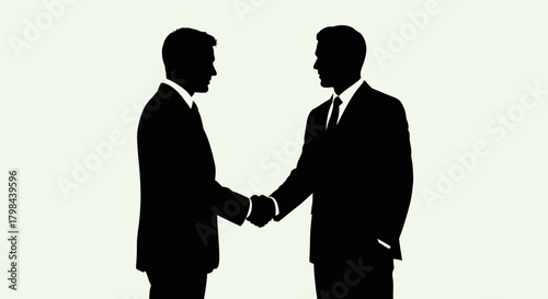 Two men in suits shake hands in silhouette