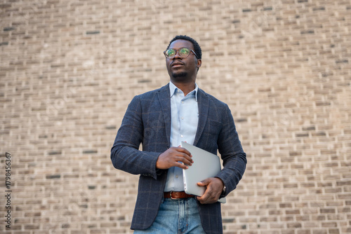 фотографія Young black man holding laptop looking confident and aspiring