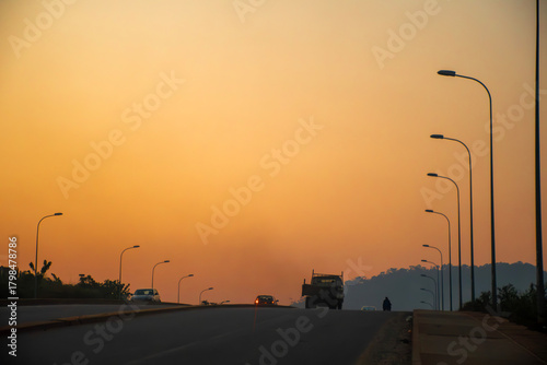 sunset in the city, golden sunset over a road in Yaoundé, Cameroon. Bathed in warm, soothing light, vehicles and streetlights stand out in silhouette.