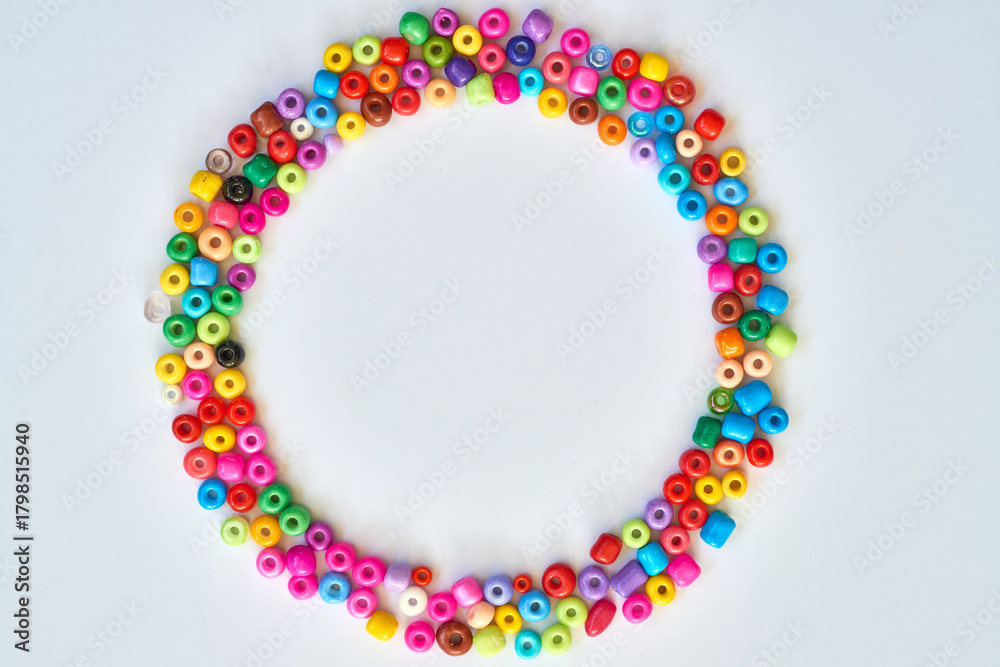 Fototapeta premium Colorful craft beads arranged in a circular pattern on a white background for creative projects