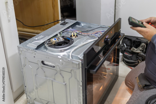 Technician checking electric wiring of kitchen oven