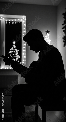 Black and white silhouette of a musician playing an acoustic guitar.