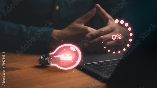 Billede på lærred Concept of low energy or stalled creativity showing hands near a laptop with a glowing light bulb at 0%, symbolizing burnout, lack of ideas, motivation drain, productivity decline, mental exhaustion
