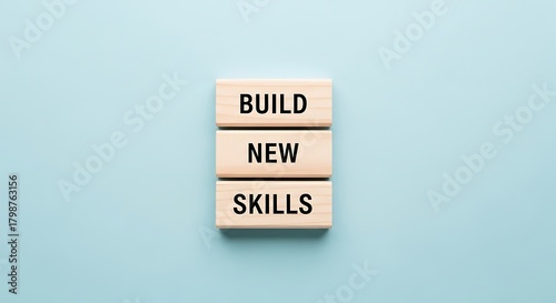 Wooden blocks stacked vertically spelling build new skills on a light blue background