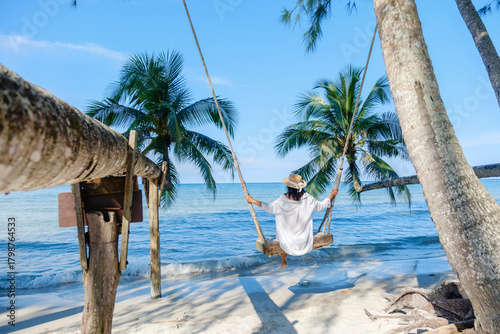Fotografia Relaxing on a beach swing under palm trees at Koh Kood Island in Thailands tropi