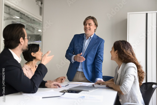 Friendly smiling experienced businessman involve diverse executives in boardroom discussion