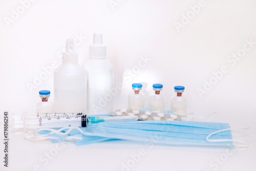 A still life of medical syringes and medication vials. Disposable syringes, medical masks, and fever pills. Supplies for injections and virus protection. 