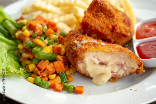 Obraz na plátne A close-up shows a plated meal of Chicken Cordon Bleu, cut to reveal melted cheese and ham