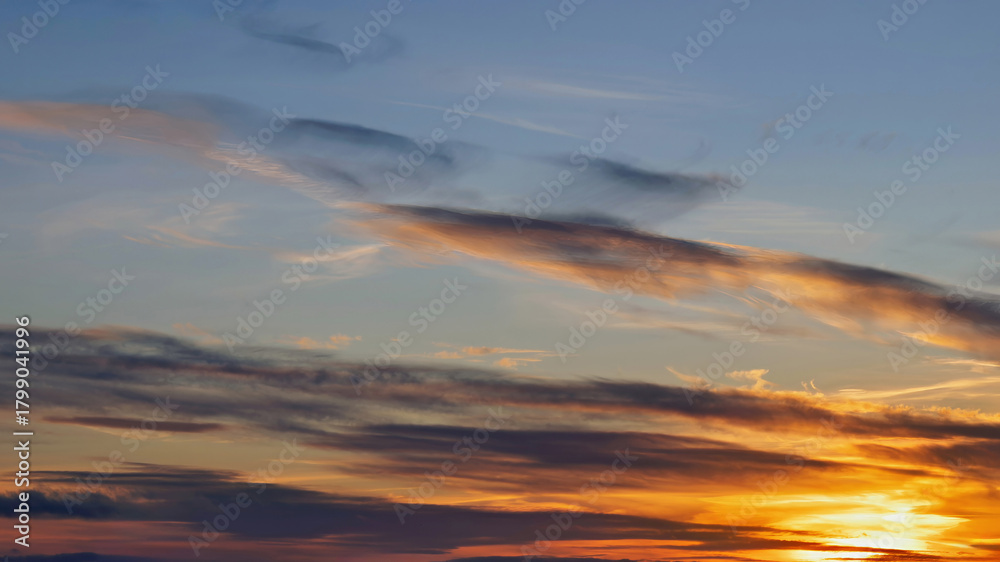 Fototapeta premium Sunset colors on a calm horizon with thin clouds creating a dramatic sky