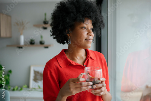 Quadro su tela Black woman contemplating by window holding coffee mug