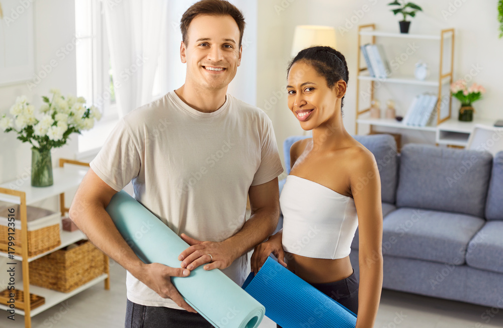 Obraz premium Couple family practicing home fitness together. Smiling partners hold yoga mats for workout, fit training, exercise, wellness and lifestyle. Wellness, sport and healthy lifestyle concept.