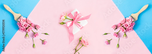 Paintbrush with pink roses and gift box on the blue and pink background. Top view.