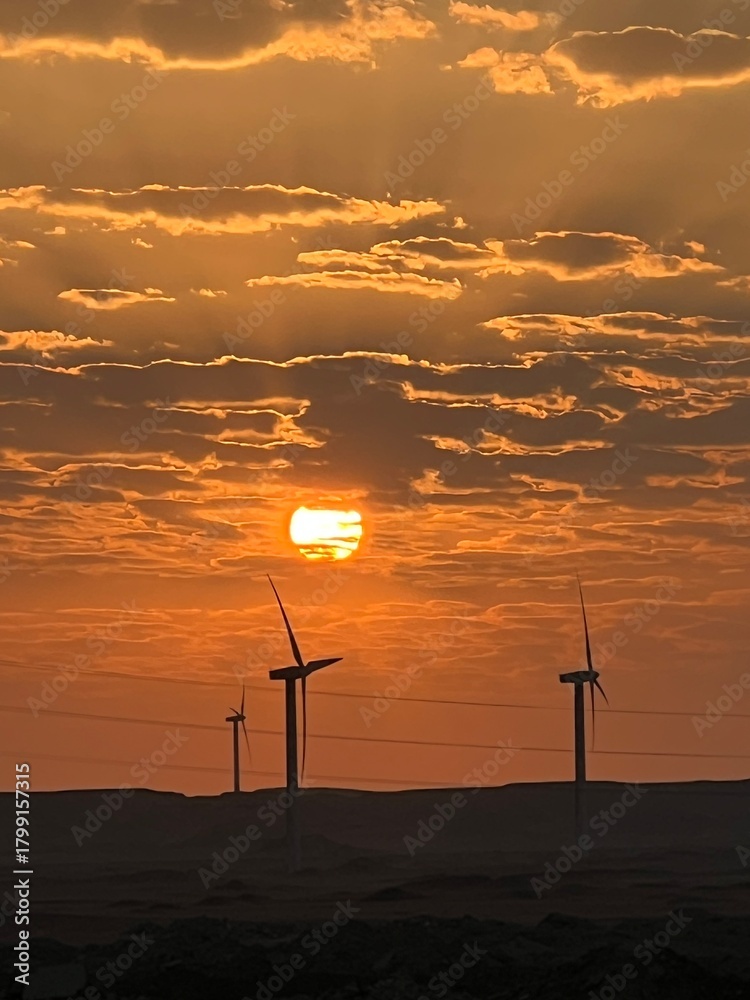 Obraz premium Orange sunset sky over wind turbines in nature landscape