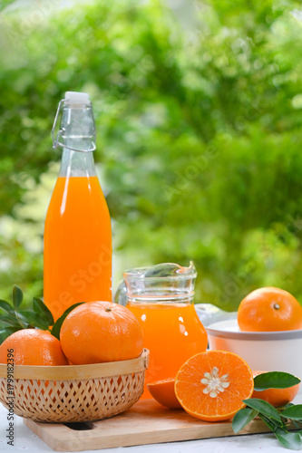 A glass of vibrant, freshly squeezed orange juice, perfectly complemented by a bright orange slice and a rustic wooden juicer, set against a backdrop of nature.