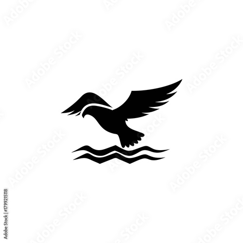 Black silhouette of an eagle flying above water, wings spread, landing or taking off.
