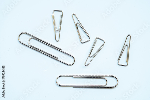 Slika na platnu A scatter of six silver paper clips on a light blue-white background