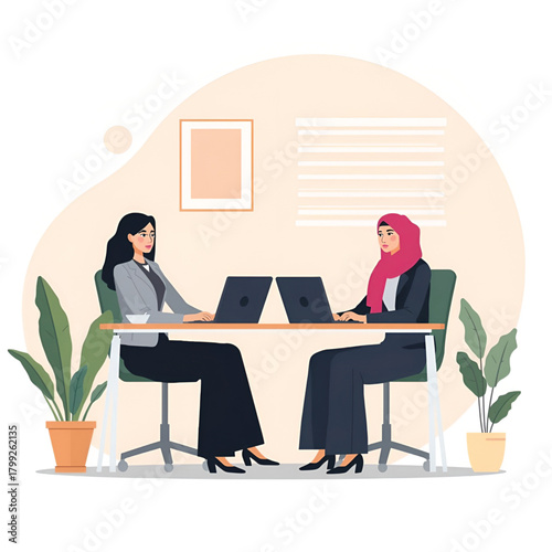Business two women, one wearing a hijab, working on laptops at a table