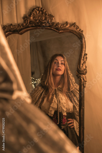 Queen in the Mirror. Emotional vintage warm portrait with candles around 