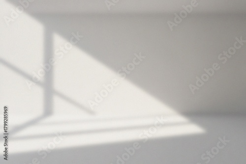 A minimalist interior with sunlight casting shadows. The scene evokes a sense of tranquility and simplicity