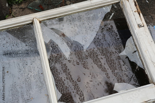 Fenêtre en bois cassée posée dans la rue sous la pluie