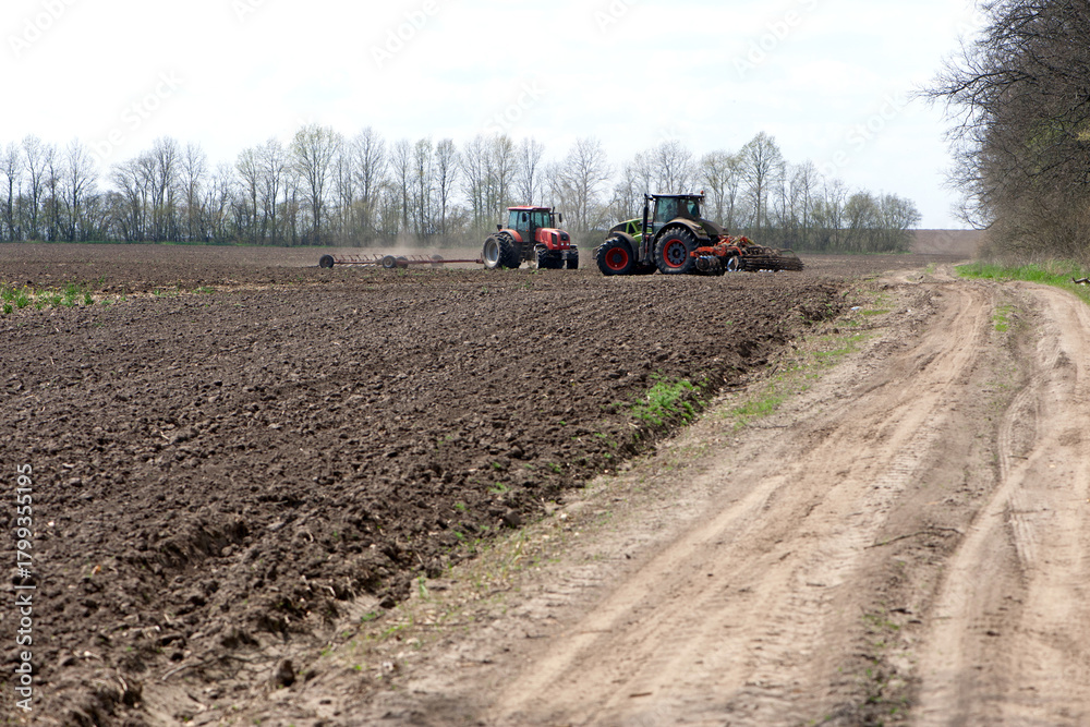 Fototapeta premium Kyiv, Ukraine. 05.01.2021. two tractors in a field, agricultural field. tractor working in the field, harvesting, business, agriculture. soil preparation, spring season. farming in Ukraine. editorial