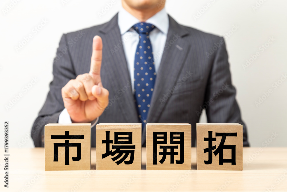 Obraz premium 「市場開拓」と書かれたブロックとビジネスマン